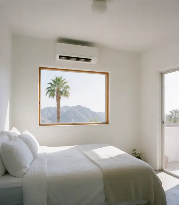 Inside the casita: a ductless head on the wall above a window that frames a palm